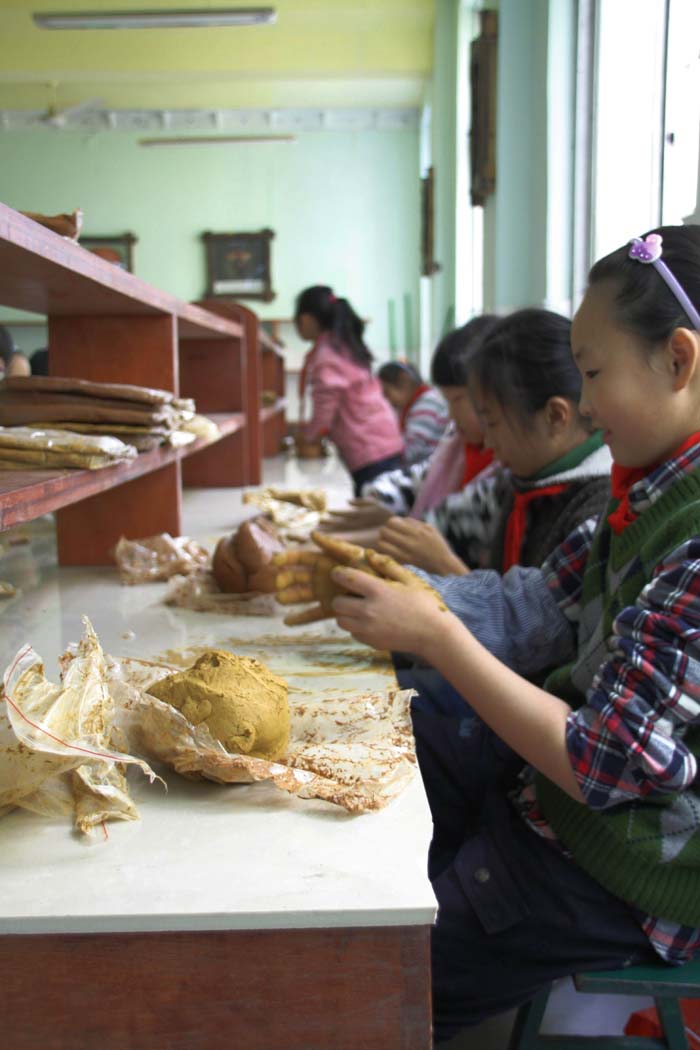 孩子们在老师的指导下学习陶艺